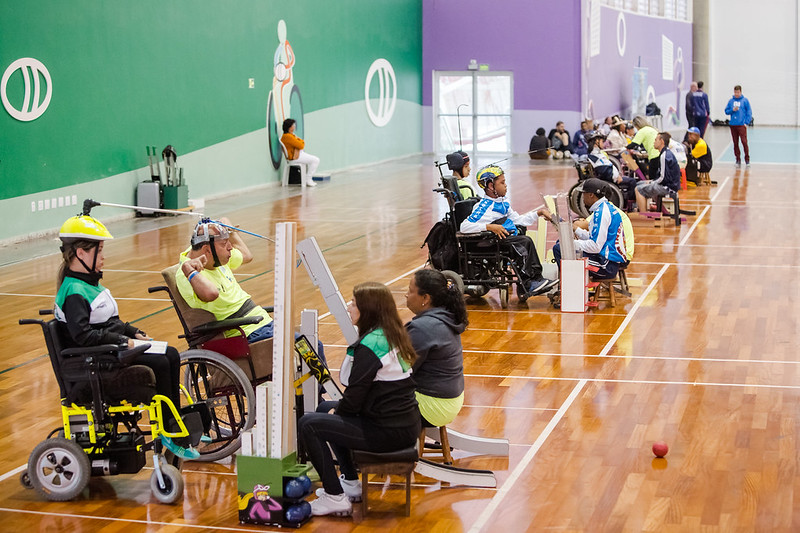 Quadra de esporte com atletas paralímpicos praticando esportes